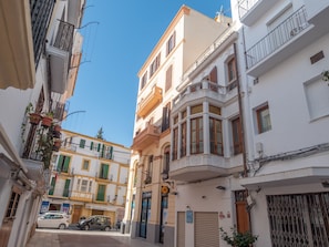 Une rue étroite bordée de bâtiments des deux côtés, avec des balcons et un mélange de styles architecturaux.