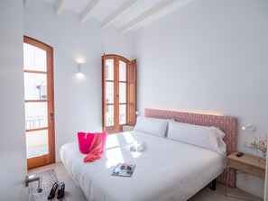 Een slaapkamer met een groot bed, een houten nachtkastje, een rode kussen en een raam met uitzicht op het omliggende landschap.