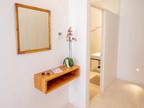 A hallway with a wooden console table, a mirror, and a vase with flowers.