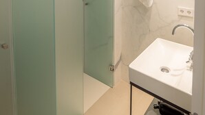 A modern bathroom with a glass shower enclosure, a marble wall, and a white sink with a mirror. - New duplex in Ibiza center with Dalt Vila views (Ibiza)