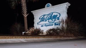 Een bord met 'The Culver at Oyster Bay', met een palmboom en struiken op de voorgrond.