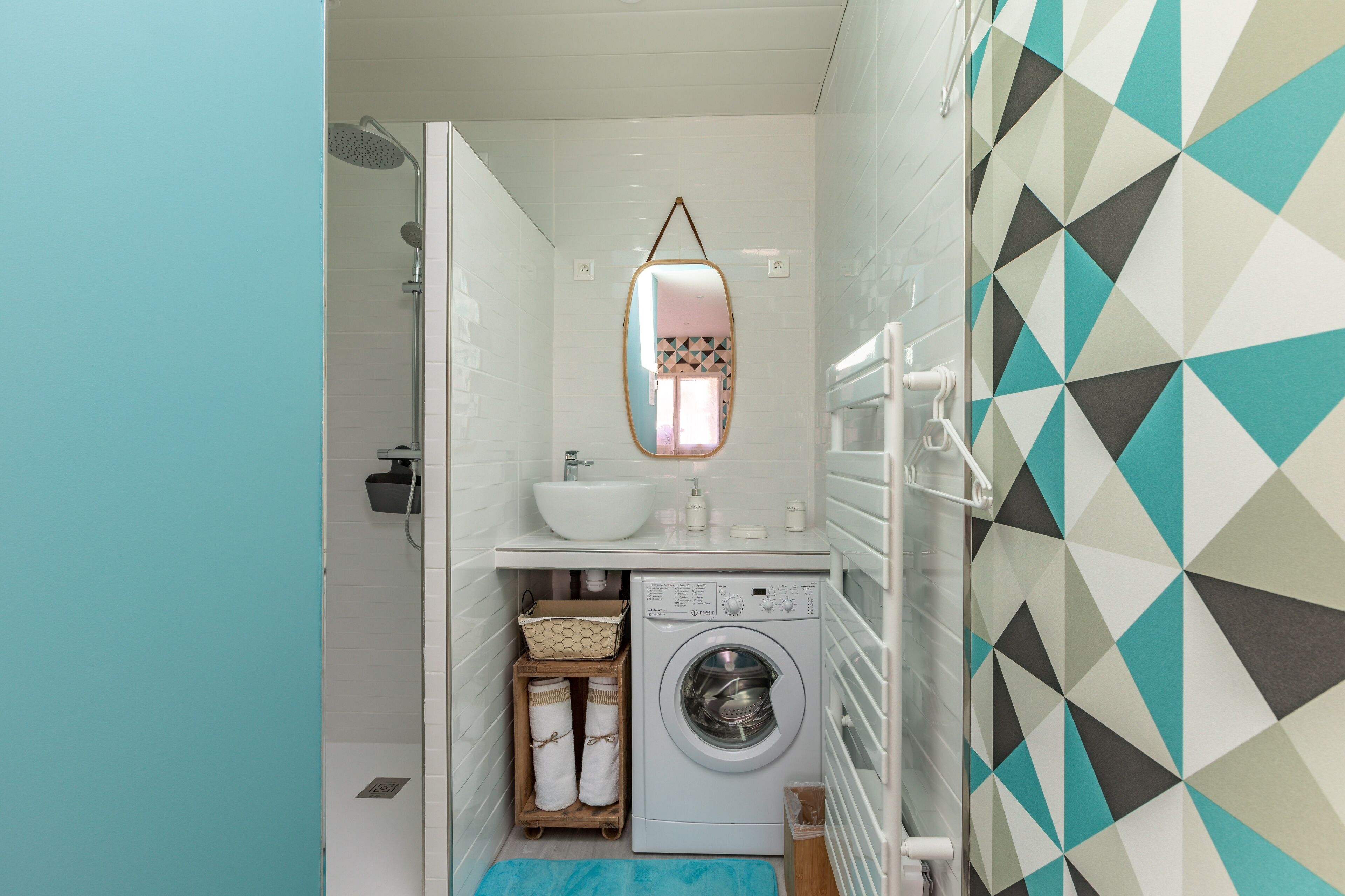 A compact bathroom with a washing machine, a sink, and a mirror.