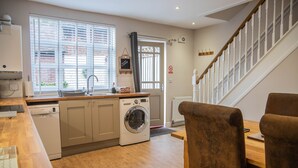 A modern kitchen with a built-in washing machine, wooden countertops, and a dining area with a wooden table and chairs. - Ironmasters House (Telford)