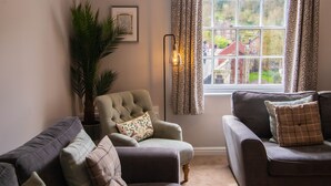 A living room with a sofa, armchair, and a large potted plant. - Ironmasters House (Telford)