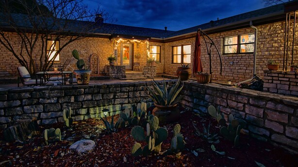 Een stenen huis met terras, cactussen en een zwembadje.