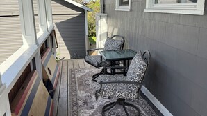 Un patio techado con mesa y sillas, un tapete estampado y una terraza de madera.