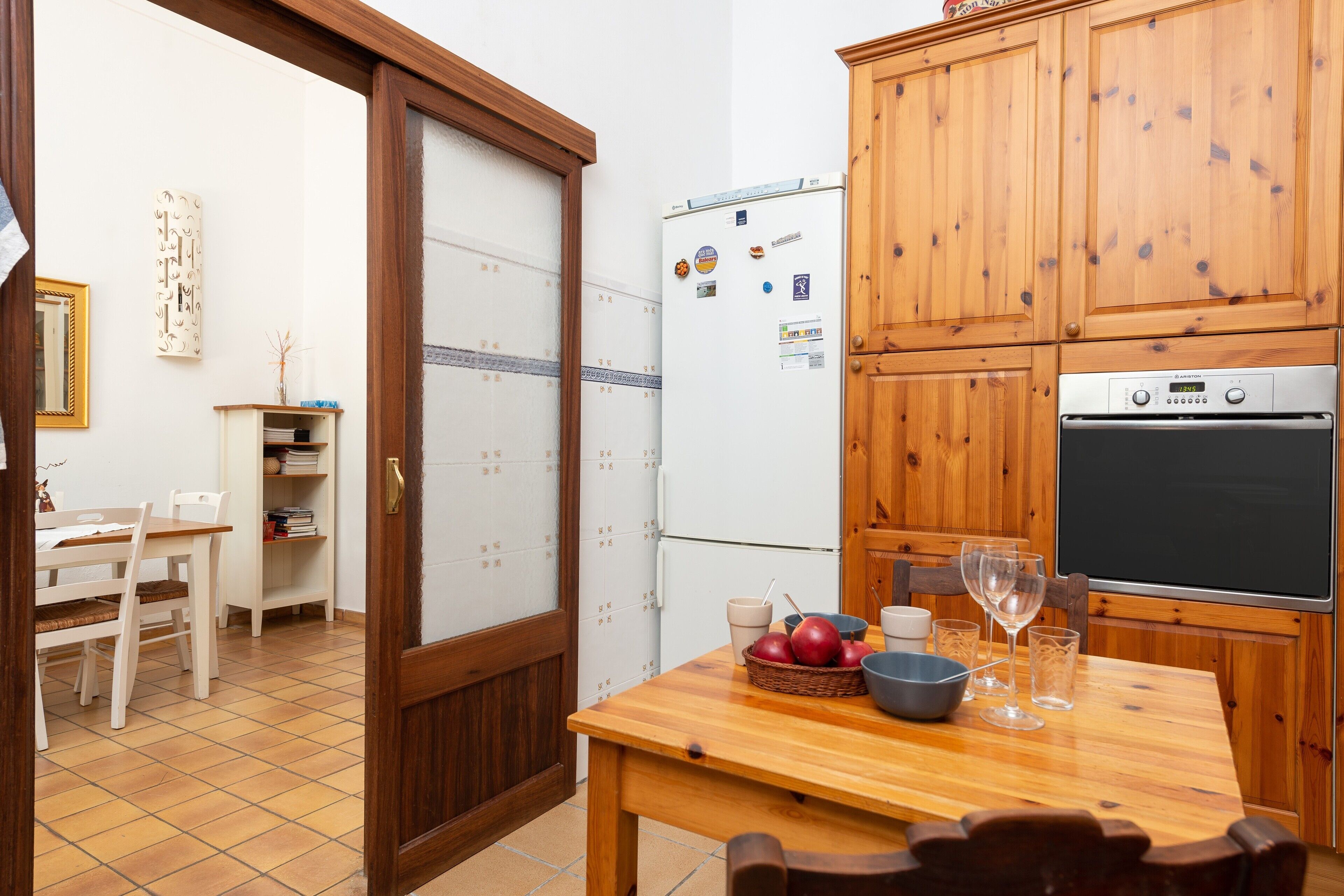 Una cocina compacta con armarios de madera, un refrigerador y un horno empotrado.