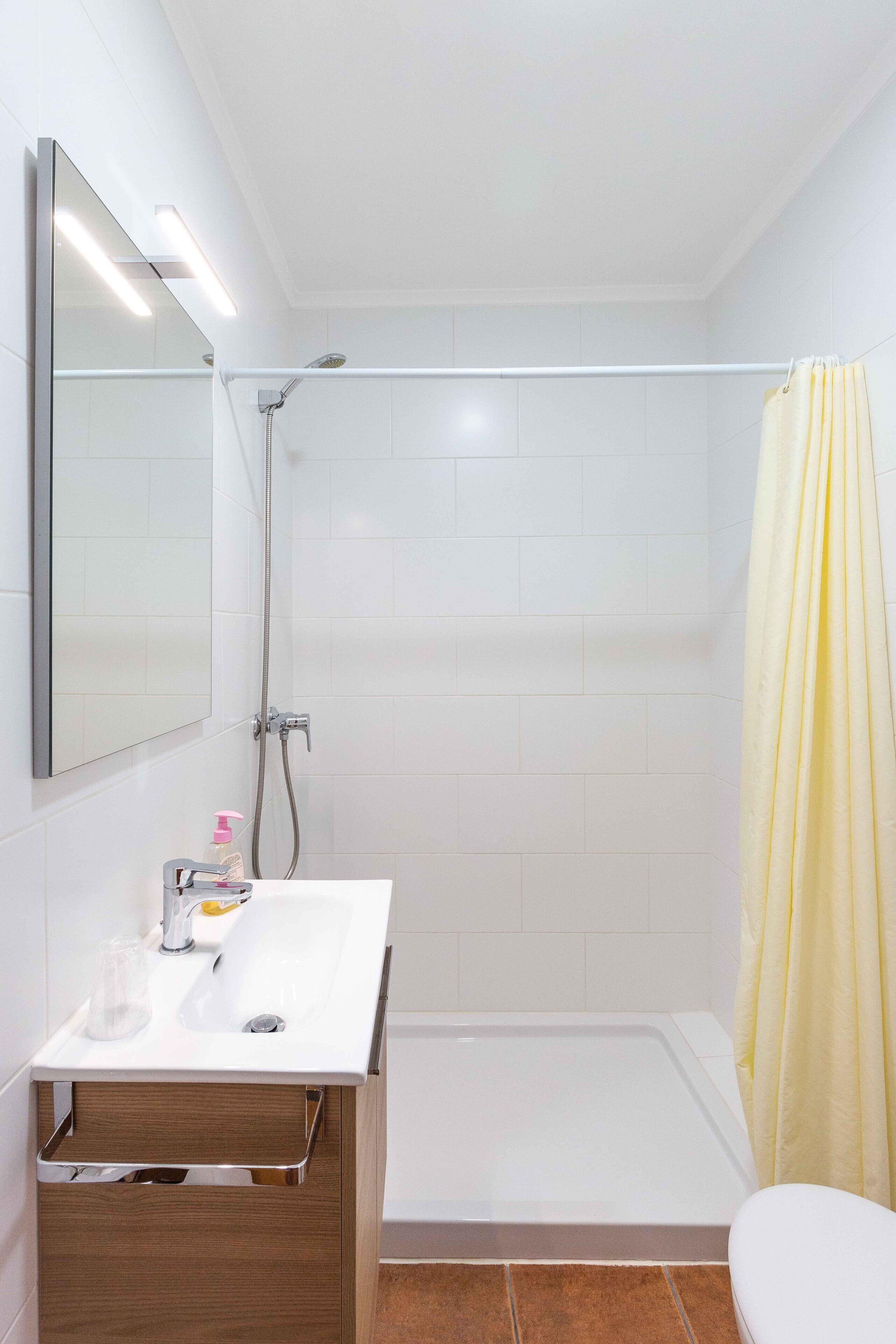 A modern bathroom with a white sink, mirror, and shower.
