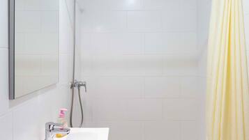 A modern bathroom with a white sink, mirror, and shower.