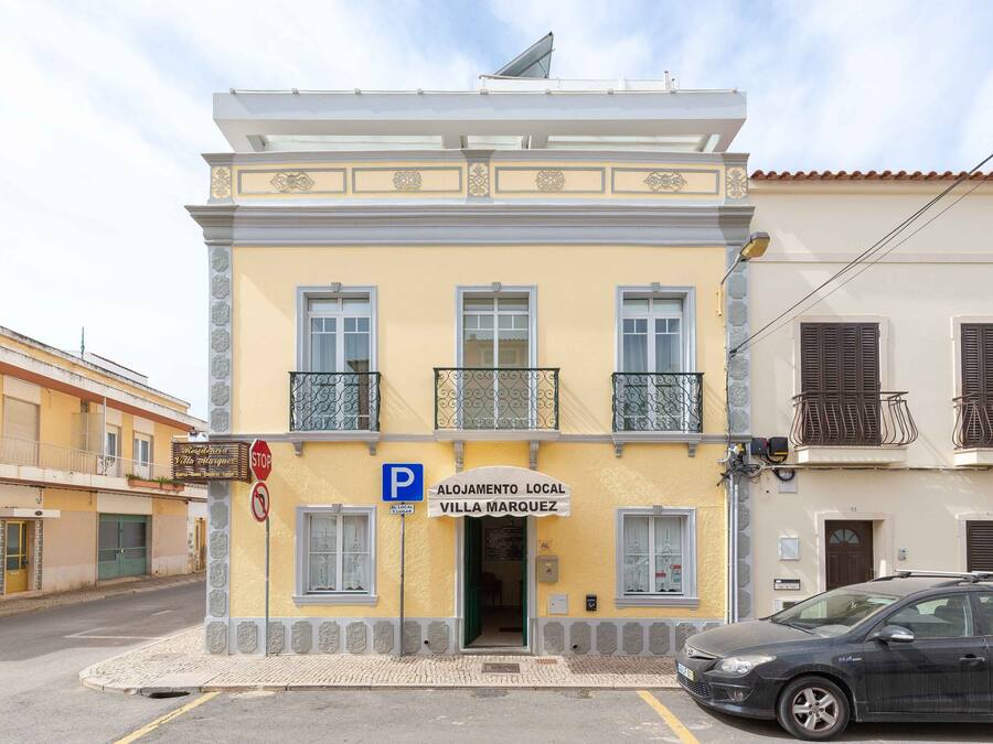 A two-story building with a sign reading "Alojamento Local Villa Marquez".
