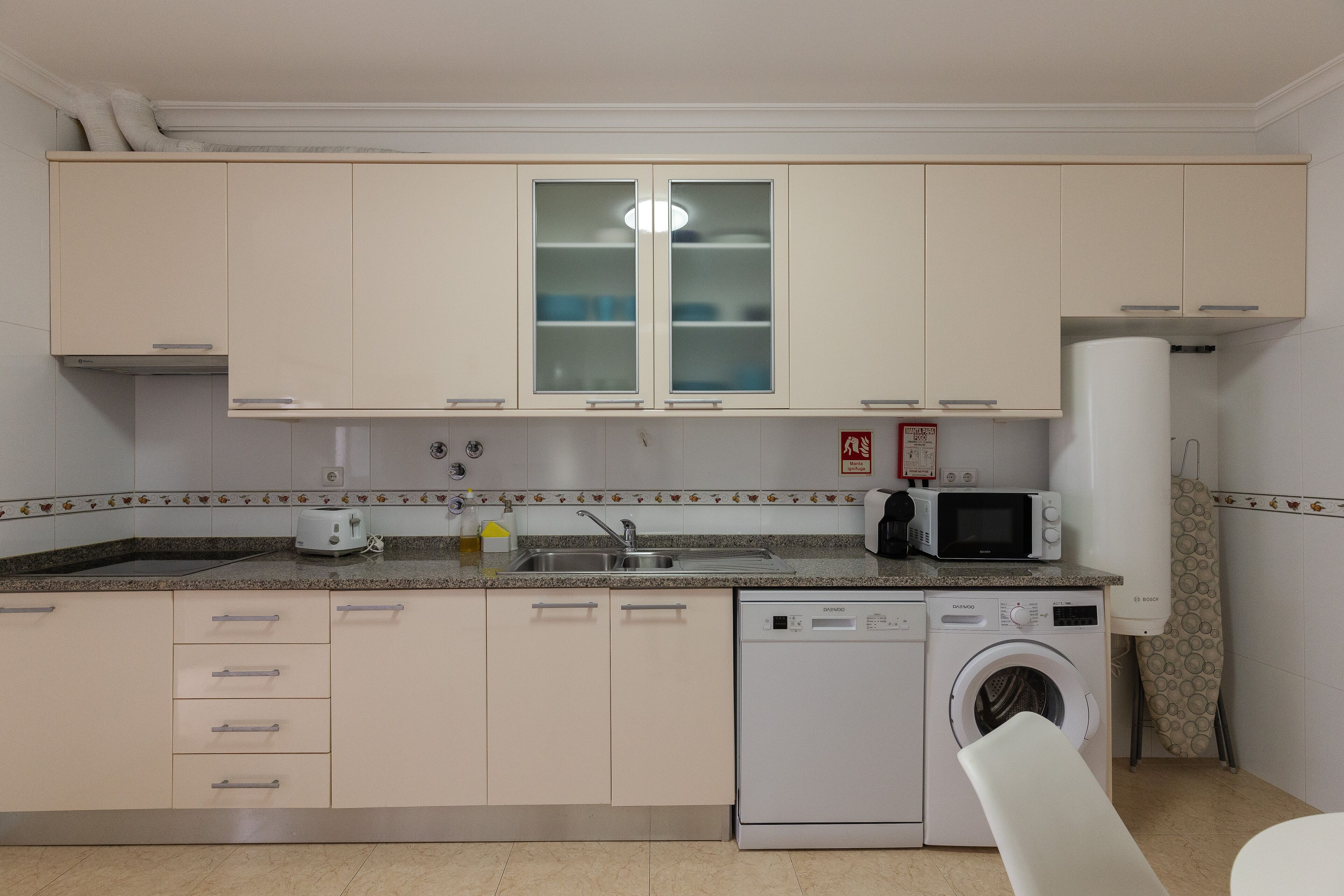 Cocina compacta con lavadora, microondas y fregadero.