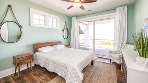 Une chambre à coucher avec un lit, un ventilateur de plafond, une fenêtre et une vue sur l’extérieur.