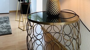 Ein modernes Wohnzimmer mit einem Glastisch, einer dekorativen Ananaslampe und einer hohen Pflanze.