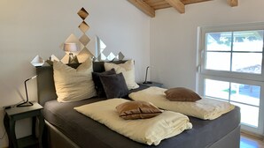Ein modernes Schlafzimmer mit einem Bett, Nachttischen und einem Fenster.