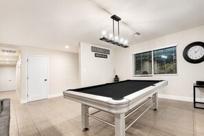 A pool table in a room with a sign reading 'FAIRBANKS ALASKA' on the wall, a clock, and a window with blinds. - ScottsdaleStays 9BR-6BA Multimillion Estate-Huge Yard-Pickleball-The Best Area. (Scottsdale)