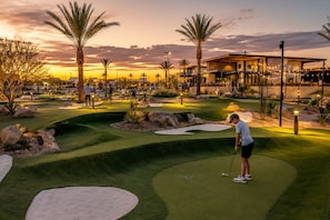 A golf course at dusk with a well-lit clubhouse in the background.