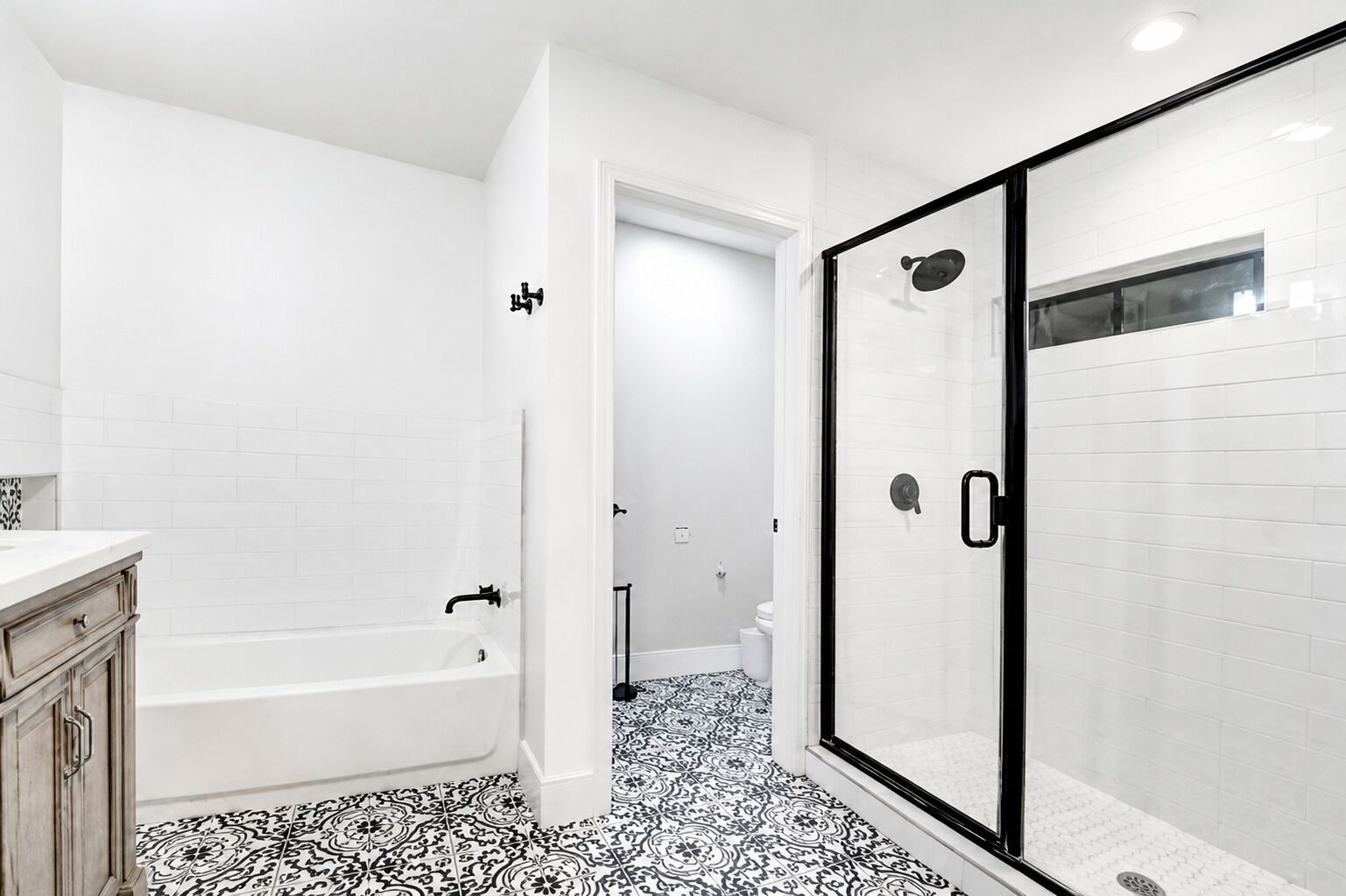 Un bagno con vasca, doccia a porte di vetro e pavimento con piastrelle decorate.