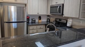 Una cucina moderna con frigorifero in acciaio inossidabile, forno a microonde, piano cottura a gas e lavello.
