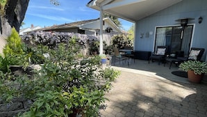 A covered patio area with hexagonal paving, outdoor furniture, and potted plants. - Lovely private guest suite w/hot tub/grill/kitchenette (Eugene)