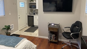 A compact bedroom with a bed, a bedside table, a chair, and a TV mounted on the wall. - Lovely private guest suite w/hot tub/grill/kitchenette (Eugene)
