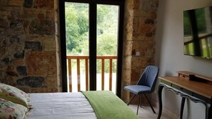 Un dormitorio con cama, escritorio, silla y televisor en la pared.