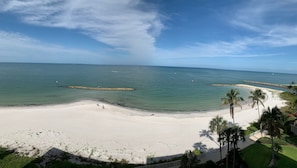 Una playa con aguas cristalinas, una orilla arenosa y palmeras.