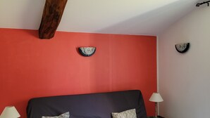 A room with a bed, two nightstands, and a red accent wall. - Quiet gite - 20 mn from Royan, 10mn from Saintes (Retaud)