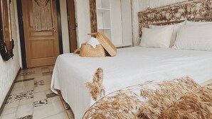 A bedroom with a large bed, a woven basket, and a macrame wall hanging. - Afet Inn Hotel (Cesme)