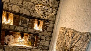 A stone fireplace with a hanging light fixture and a decorative wall piece. - Afet Inn Hotel (Cesme)