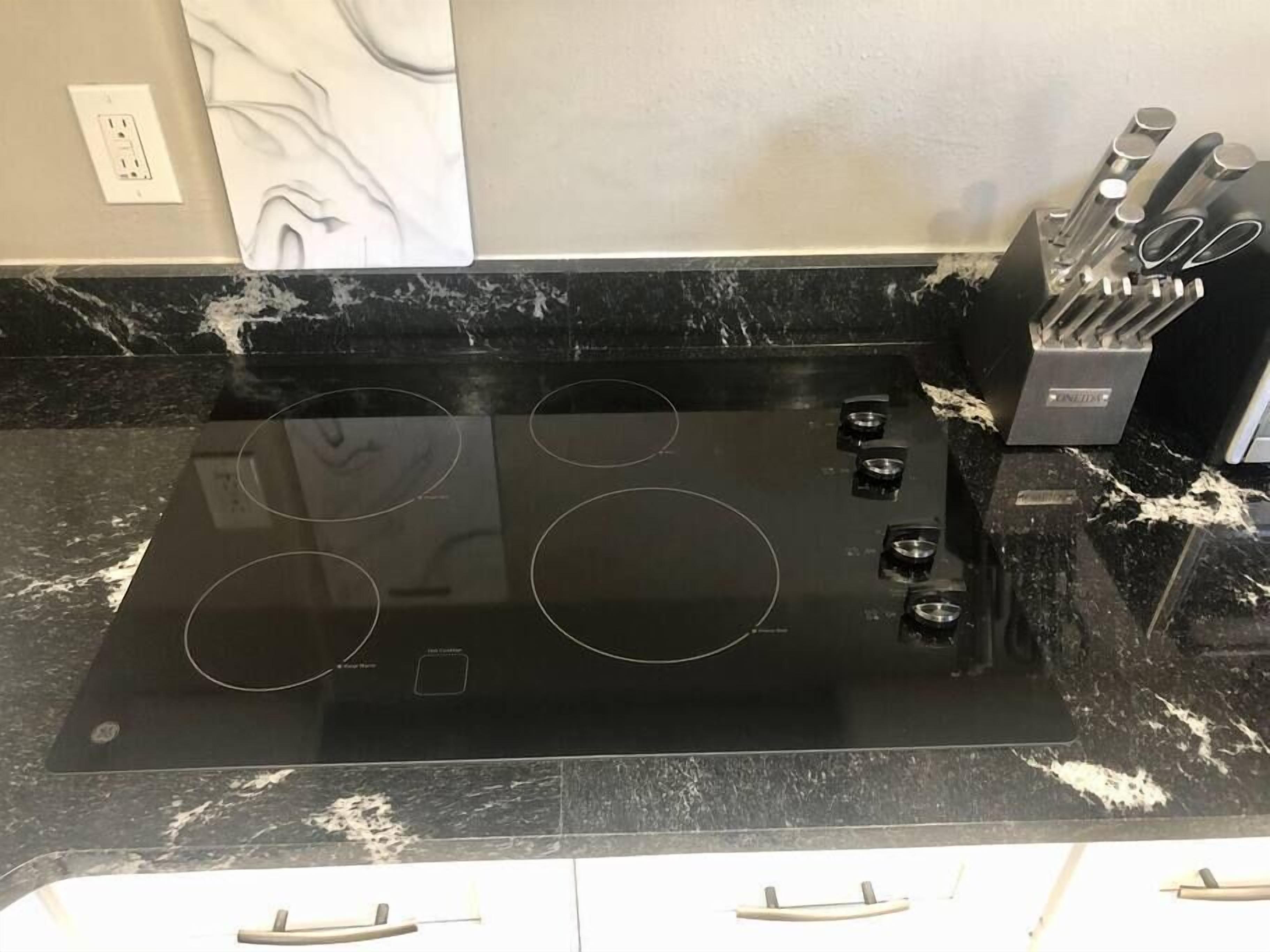 Una cocina con tope negro y estufa de cuatro quemadores.