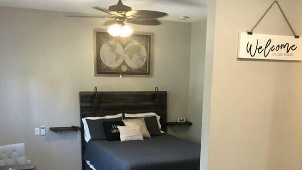 A bedroom with a bed, a ceiling fan, a 'Welcome' sign, a dining table with chairs, and a staircase. - "The Sweet Suite" - Private & Quiet, Near 408/417 (Orlando)