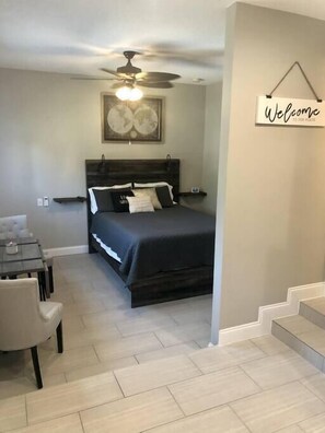 A bedroom with a bed, a ceiling fan, a 'Welcome' sign, a dining table with chairs, and a staircase. - "The Sweet Suite" - Private & Quiet, Near 408/417 (Orlando)