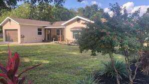 A two-story house with a front porch, a garage, and a well-maintained lawn with various plants. - "The Sweet Suite" - Private & Quiet, Near 408/417 (Orlando)