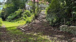 Una casa rodeada de vegetación exuberante y un muro de piedra.