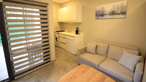 A compact living space with a kitchenette, a sofa, and a painting on the wall. - YALIN APART HOTEL (Bodrum)