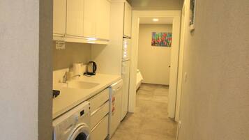 A compact kitchen with a washing machine, a sink, and a refrigerator.