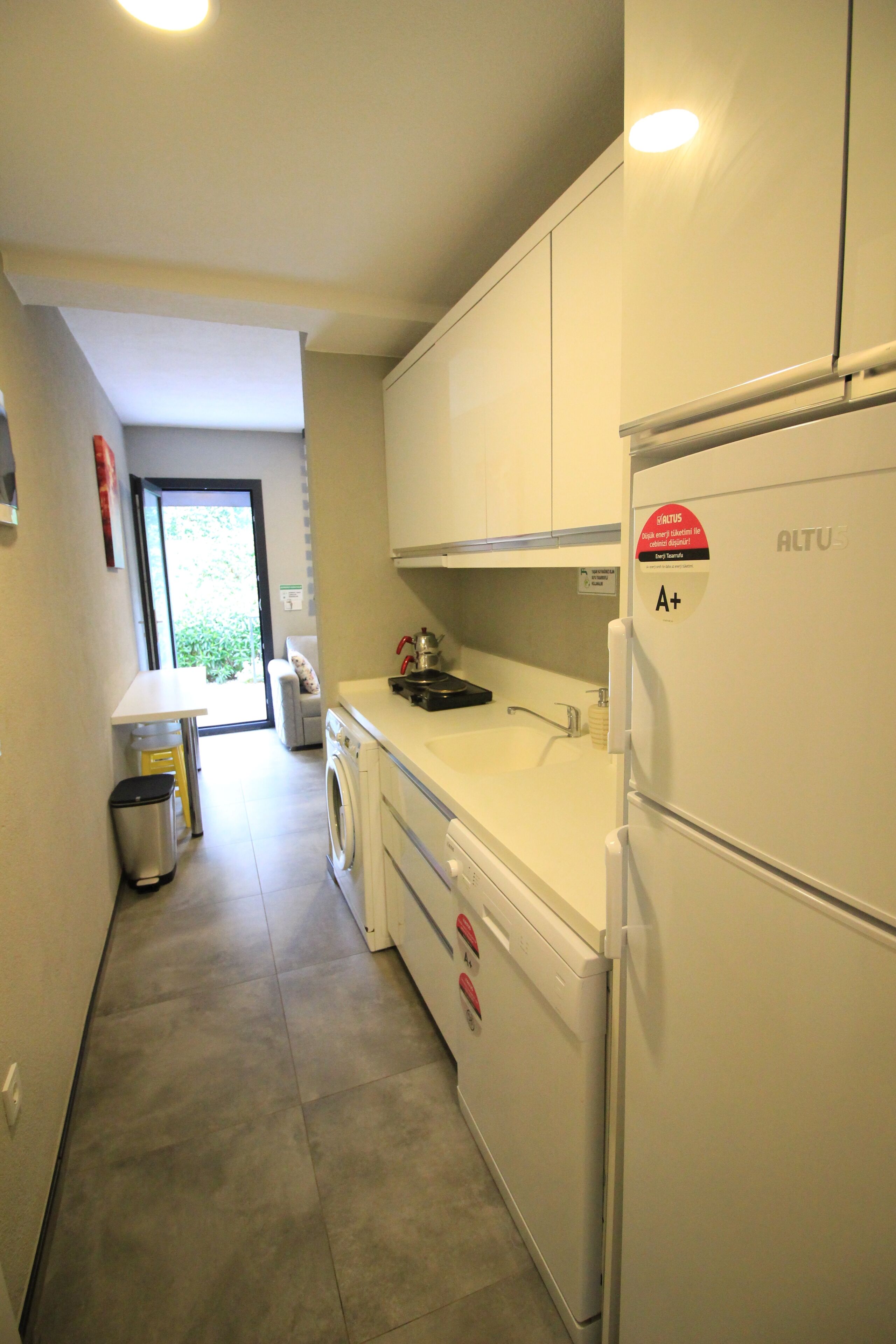 A compact kitchen with white cabinets, a washing machine, and a refrigerator.