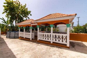 A covered outdoor seating area with a tiled roof and white balustrades.