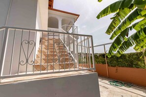 A staircase with metal railings leading to a white building with a balcony.
