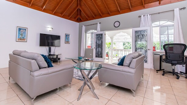 A spacious living room with two sofas, a glass coffee table, a TV, and a large window with curtains. - Runaway Bay Gem, Spacious and Bright, 5 mins drive to the Beach! (Runaway Bay)