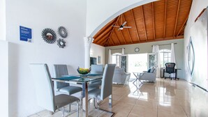 A modern dining area with a glass table and metal chairs, a wooden ceiling, and a view of the outdoors. - Runaway Bay Gem, Spacious and Bright, 5 mins drive to the Beach! (Runaway Bay)