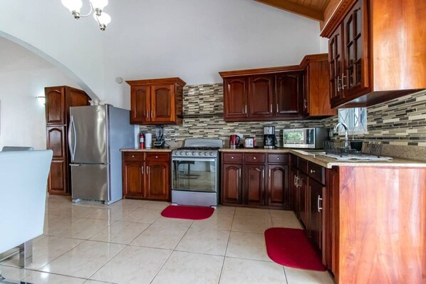 A kitchen with wooden cabinets, a stainless steel refrigerator, a stove, and a microwave.