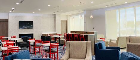 A hotel lobby with seating areas, a reception desk, and a large window providing natural light.