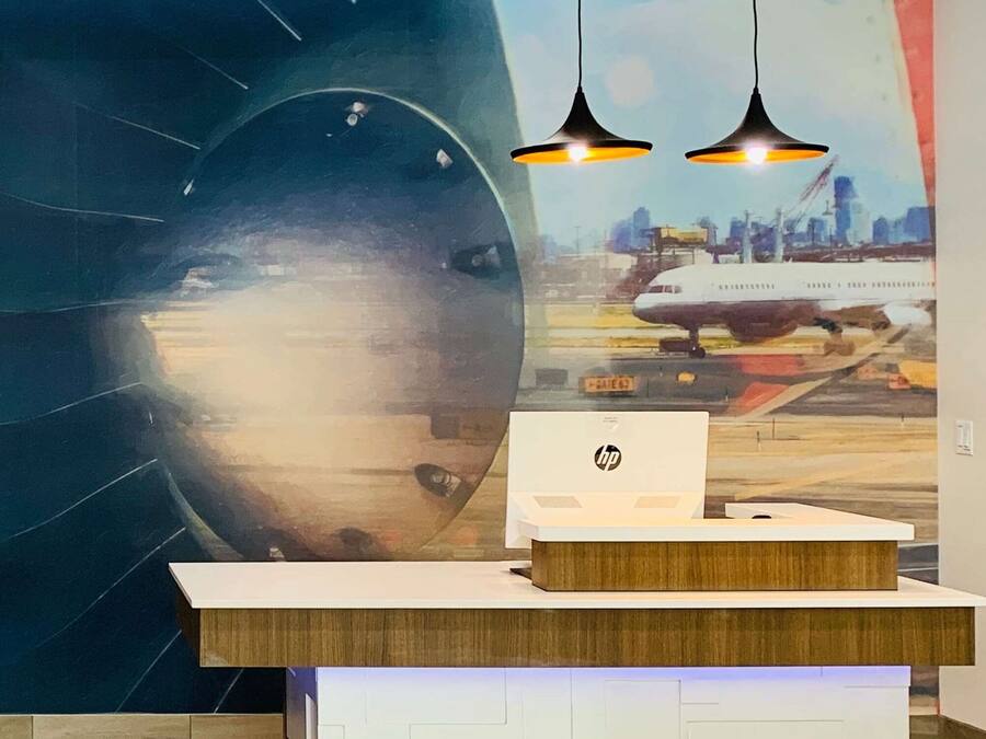 Un comptoir d’accueil orné d’une fresque représentant un paysage urbain, deux lampes suspendues et le logo HP sur le comptoir.