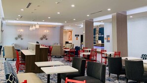 Un vestíbulo de hotel con zonas de estar, mesas y una recepción.