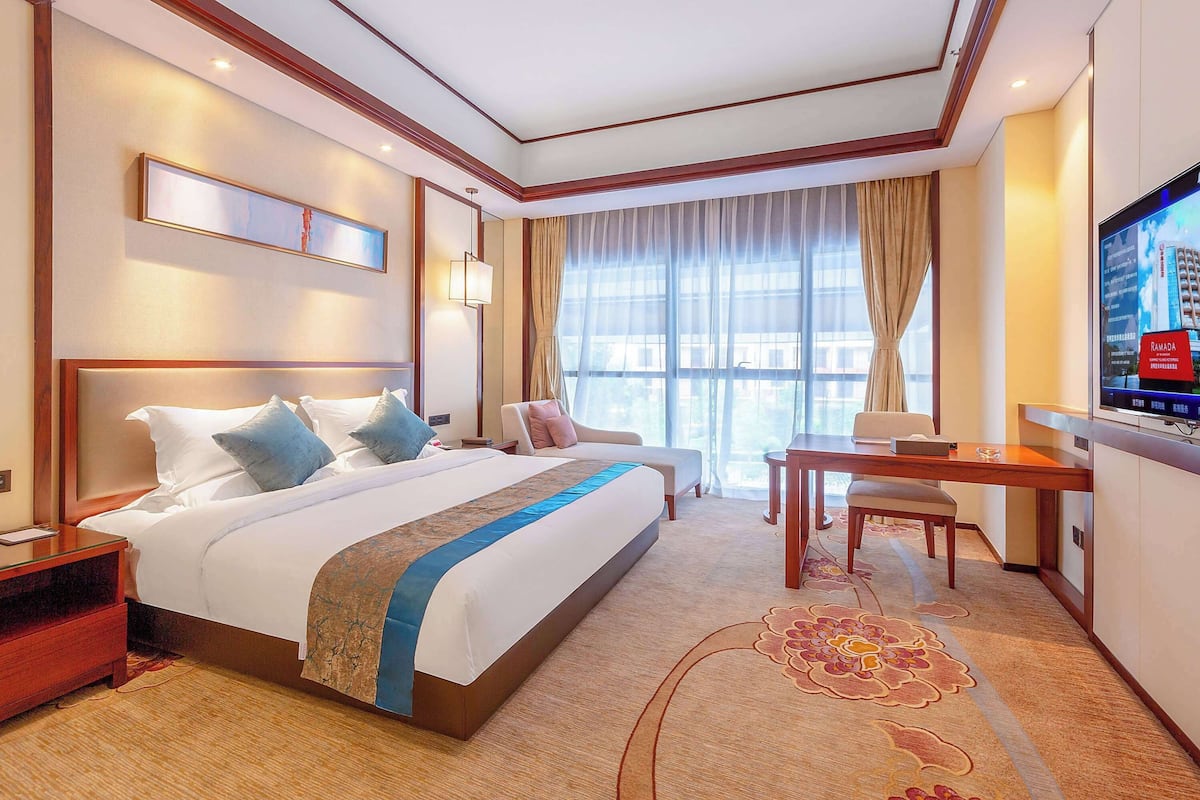 A hotel room with a large bed, a desk, and a television.