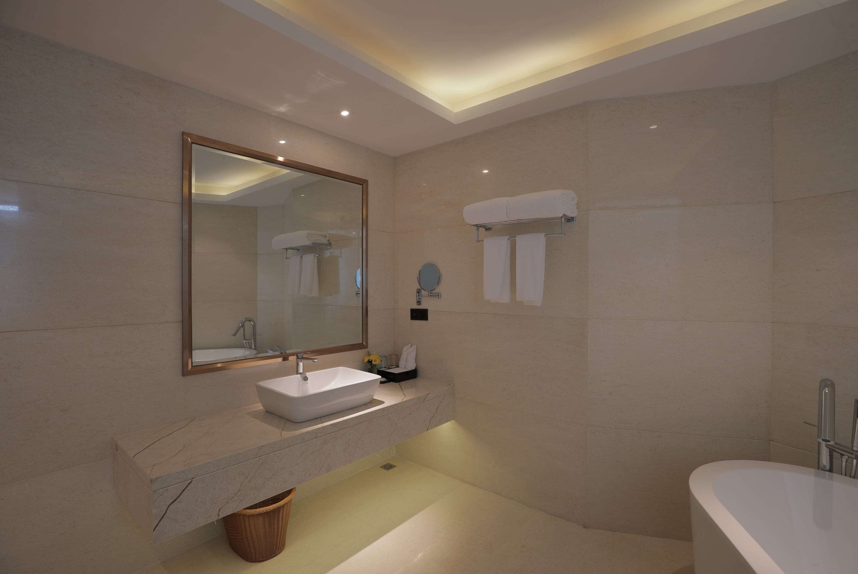 Un baño moderno con un espejo grande, un lavamanos, una bañera y un perchero para toallas.
