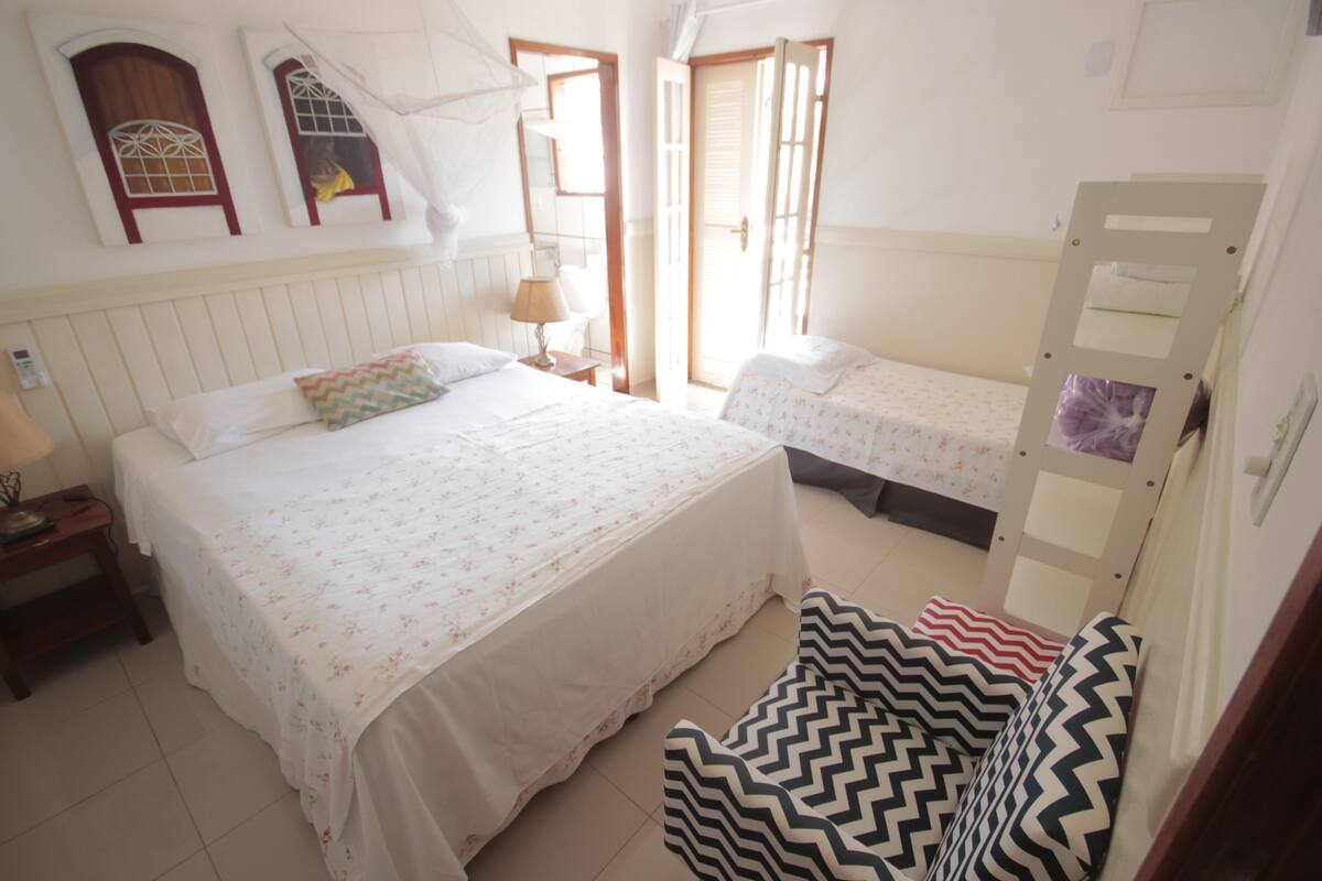 A room with two beds, a nightstand, a chair, and a wooden ladder.
