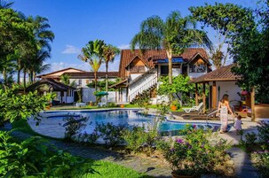 Una piscina al aire libre, sombrillas, sillones reclinables de piscina