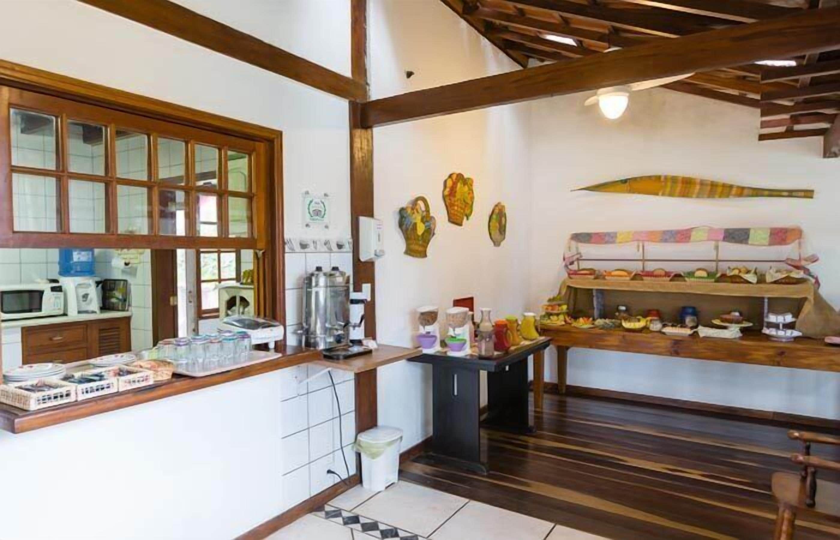 Uma cozinha com vigas de madeira, uma janela e uma prateleira com diversos utensílios de cozinha.